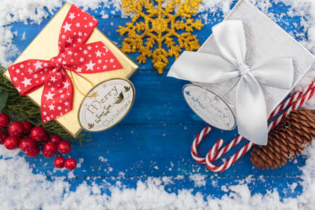 Top view of christmas gift boxes and decoration on blue wooden table with snowの写真素材
