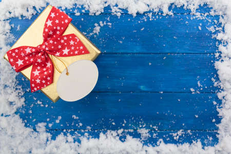 Christmas background with gift box on blue wooden table with snow. Top view with copy spaceの写真素材