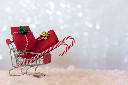 Shopping cart full of christmas gifts on snowy background with copy spaceの写真素材
