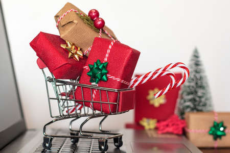 Shopping cart with christmas gifts on laptop computer. Online shopping, e-commerce and worldwide shipping conceptの写真素材
