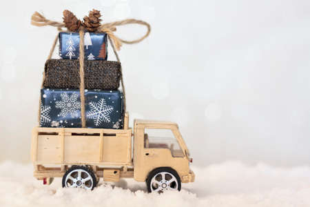 Handmade wooden Christmas truck with christmas gifts on snowy roadの写真素材