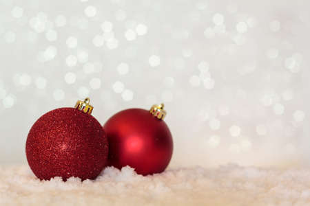 Red Christmas balls on table with snow and festive background with copy spaceの写真素材