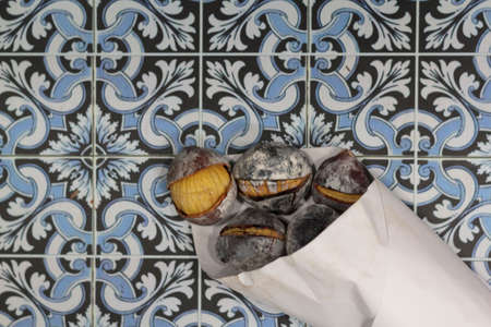 Top view of Paper cone with roasted chestnuts on Portuguese tiles backgroundの写真素材