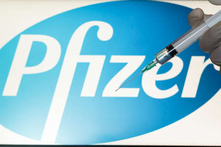 Lisbon, Portugal - November 22, 2020: Syringe and Pfizer logo on the background. Coronavirus, Covid-19 vaccine conceptのeditorial素材