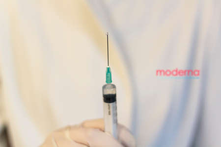 Lisbon, Portugal - November 22, 2020: Medic ,scientist, pharmacist holding Syringe with Moderna logo on lab coat. Coronavirus, Covid-19 vaccine conceptのeditorial素材