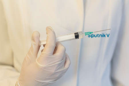 Lisbon, Portugal - November 22, 2020: Medic ,scientist, pharmacist holding Syringe with Sputnik V logo on lab coat. Coronavirus, Covid-19 vaccine conceptのeditorial素材