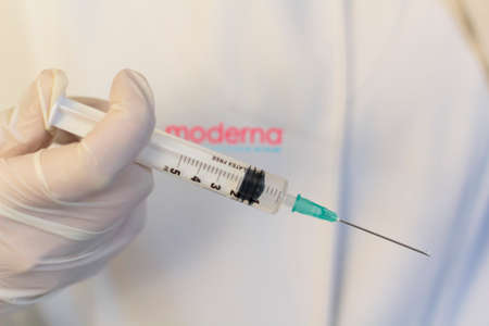 Lisbon, Portugal - November 22, 2020: Medic ,scientist, pharmacist holding Syringe with Moderna logo on lab coat. Coronavirus, Covid-19 vaccine conceptのeditorial素材