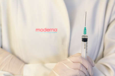 Lisbon, Portugal - November 22, 2020: Medic ,scientist, pharmacist holding Syringe with Moderna logo on lab coat. Coronavirus, Covid-19 vaccine conceptのeditorial素材
