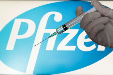 Lisbon, Portugal - November 22, 2020: Syringe and Pfizer logo on the background. Coronavirus, Covid-19 vaccine conceptのeditorial素材