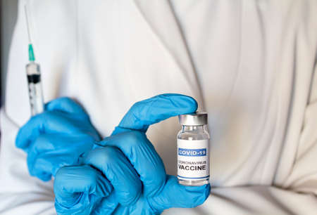 Doctor holding syringe and laboratory injection vial with Coronavirus or Covid-19 vaccineの写真素材