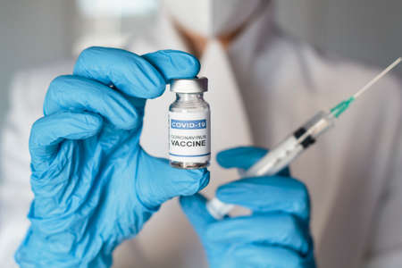 Doctor holding syringe and laboratory injection vial with Coronavirus or Covid-19 vaccineの写真素材