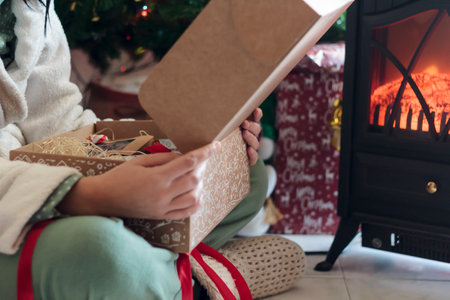 Woman open christmas gift by the Christmas treeの写真素材