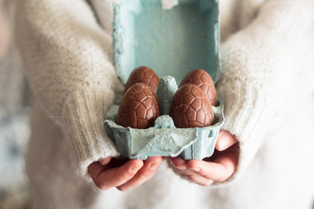 Woman holding egg carton with chocolate eggsの写真素材