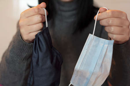 Woman holding a cloth mask and a medical maskの写真素材