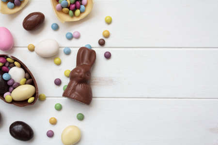 Top view of chocolate bunny and chocolate eggs on white wooden table with copy spaceの写真素材