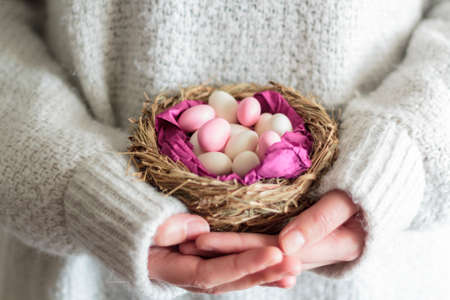 Woman hands holding a nest with sweet Easter almondsの写真素材