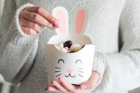 Woman hands holding rabbit box with Easter sweet eggs insideの写真素材