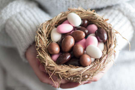Woman holding bird nest with easter sweet eggsの写真素材