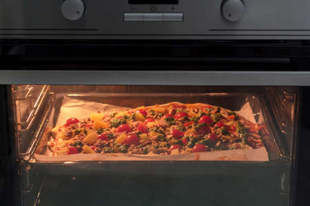 Homemade pizza cooking in the ovenの写真素材