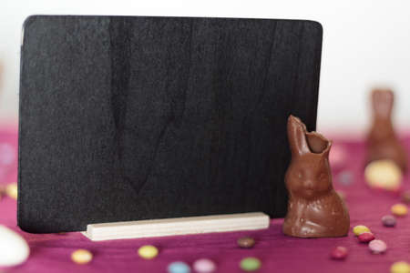 Chocolate bunny missing a bite and blackboard with copy spaceの写真素材