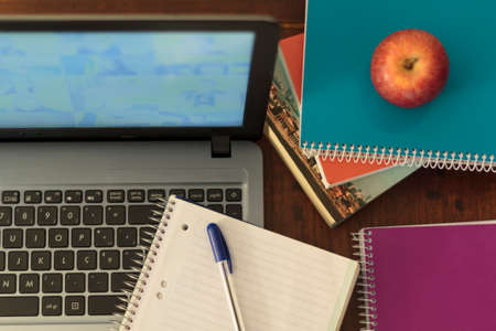Top view of computer, books, notebook, pen and apple. Online homeschoolingの写真素材