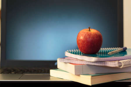 Books, notebook and apple on laptop. Online home school, e-learning conceptの写真素材
