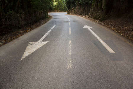 Direction arrows on empty asphalt roadの写真素材