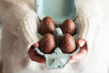 Woman hands holding egg carton with chocolate eggs. Easter celebration conceptの写真素材