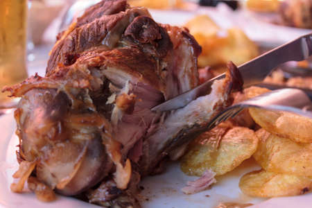 Eating roasted pork knuckle with french friesの写真素材