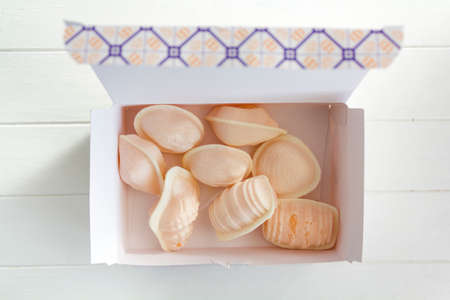 Top view of box with traditional portuguese sweet called Ovos Moles de Aveiro in white wooden tableの写真素材