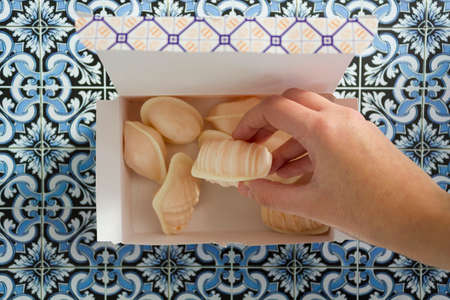 Top view woman hand taking a traditional portuguese sweet called Ovos Moles de Aveiroの写真素材