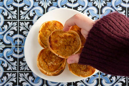 Woman hand taking a traditional portuguese cheesecake called Queijada de Sintraの写真素材