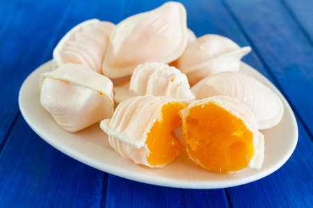 Traditional portuguese egg yolk sweets called Ovos Moles de Aveiro on blue wooden tableの写真素材