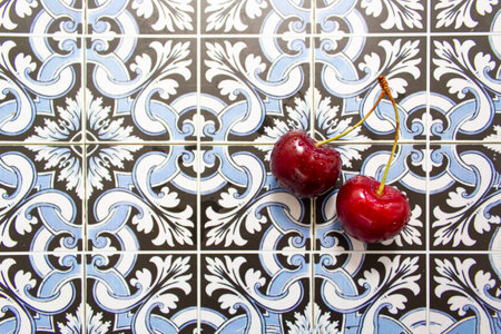 Pair of red fresh cherries on portuguese tiles backgroundの写真素材