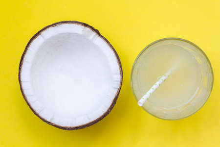 Top view of coconut and coconut water on glass with straw on yellow backgroundの写真素材