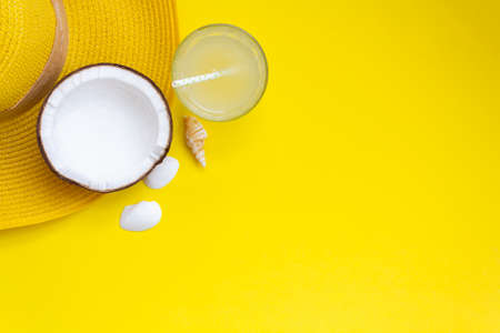 Top view of summer hat, coconut and glass with coconut water on yellow background with copy spaceの写真素材