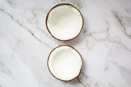 Two halves of coconut on marble background. Top viewの写真素材