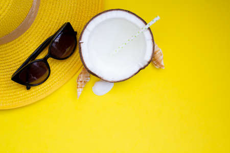 Top view of summer hat, sunglasses and coconut water on yellow background with copy space. Summer concept backgroundの写真素材