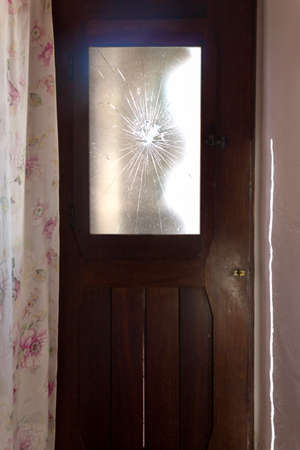 Vertical shot of old wooden door with broken glassの写真素材