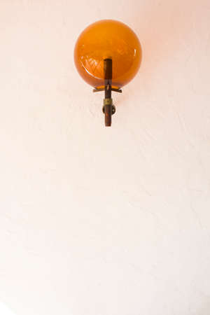 Vintage orange lamp on white wallの写真素材