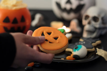 Woman holding a halloween cookie from festive tableの写真素材