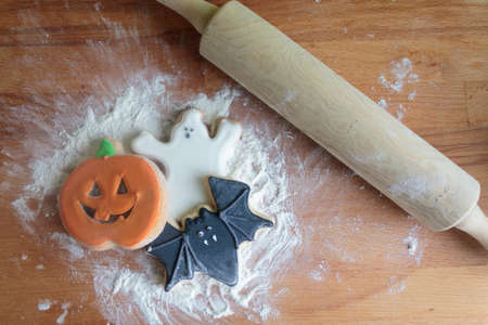 Top view of Halloween cookies on wooden board with flour and rolling pinの写真素材