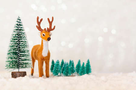 Reindeer and pine trees on snowy background with copy spaceの写真素材