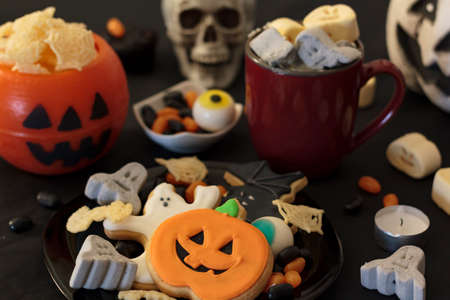 Halloween party table with snacks, cookies, treats, hot drink and halloween decorationの写真素材