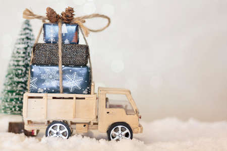 Christmas truck with christmas gifts on snowy road with christmas tree on the backgroundの写真素材