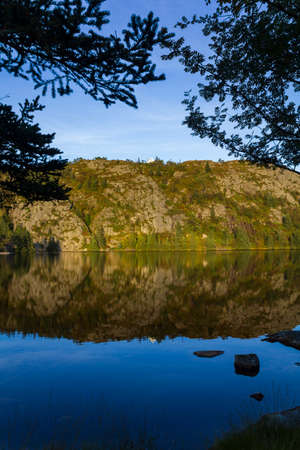 White house on top of hill with reflection in the waterの写真素材