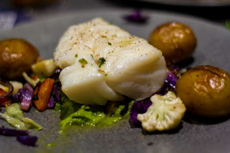 Fresh codfish with baked potatoes and vegetablesの写真素材