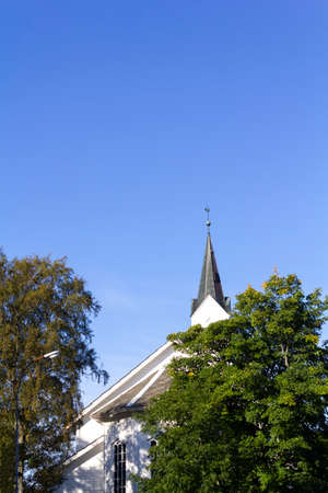 Church top and trees against blue skyの写真素材