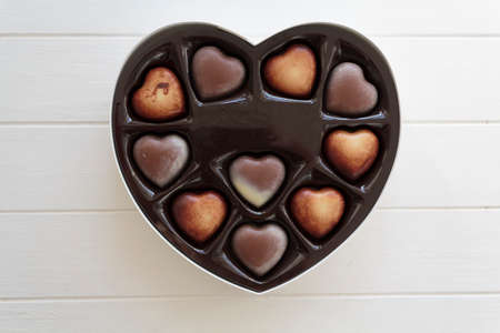 Chocolate in heart shape box on white wooden table. Top viewの写真素材