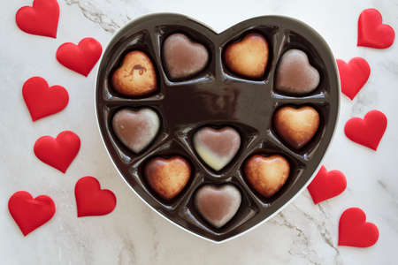 Top view of heart-shaped gift box with chocolates and red heartsの写真素材